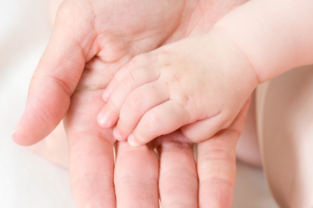bebê caucasiano com a mão na palma da mão do pai