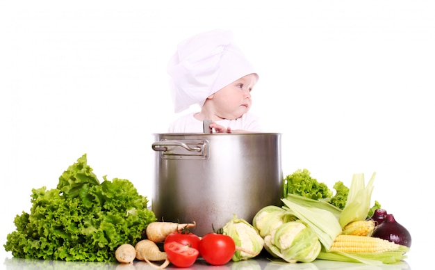 Bebê com o chef do chapéu cercado por legumes