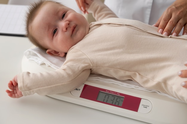 Foto grátis bebê de alto ângulo na máquina de pesagem