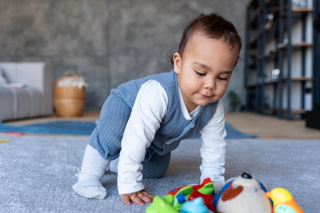 Bebê engatinhando no chão e brincando com brinquedo