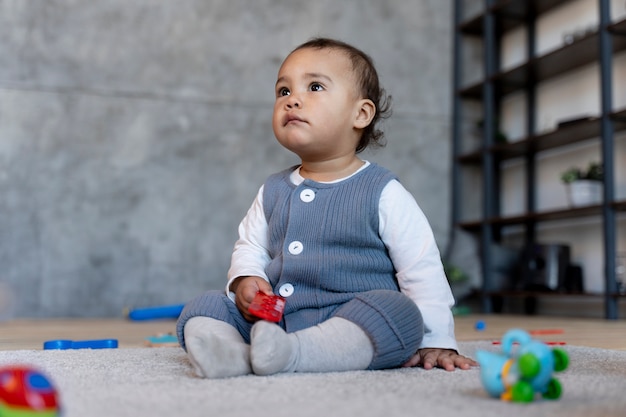 Foto grátis bebê fofo brincando no chão com brinquedo