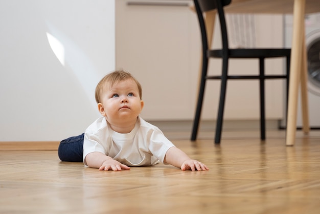 Foto grátis bebê fofo de baixo ângulo deitado no chão