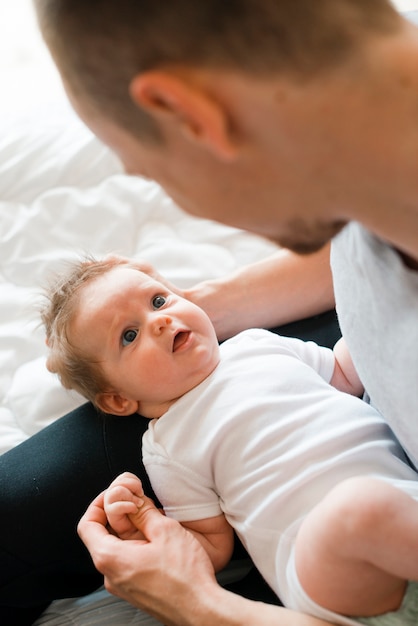 Bebê fofo deitado de joelhos de pai