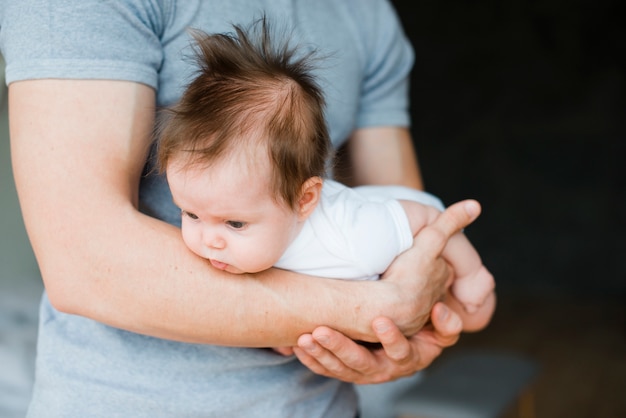 Bebê fofo deitado nas mãos do pai