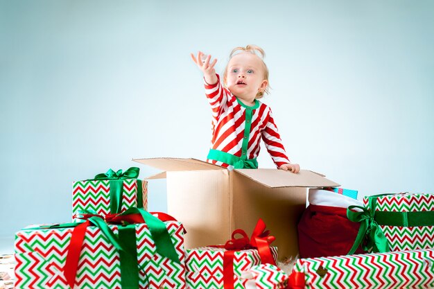 Bebê fofo menina de 1 ano de idade sentada na caixa sobre o fundo de natal. feriado, celebração, conceito de criança