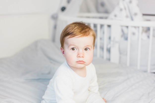 Bebê loiro bonito na cama branca