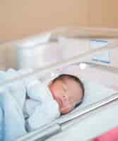 Foto grátis bebê recém-nascido dorme no berço do hospital em roupas de recém-nascido