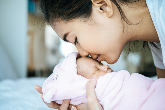 bebê recém-nascido dormindo nos braços da mãe e perfumado na testa do bebê