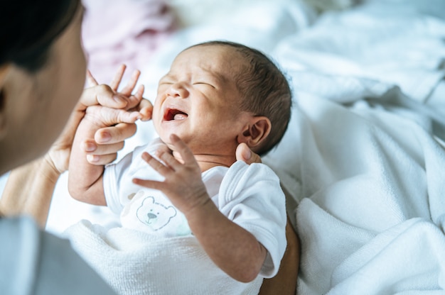 Foto grátis bebê recém-nascido usava um branco e chorou nos braços da mãe