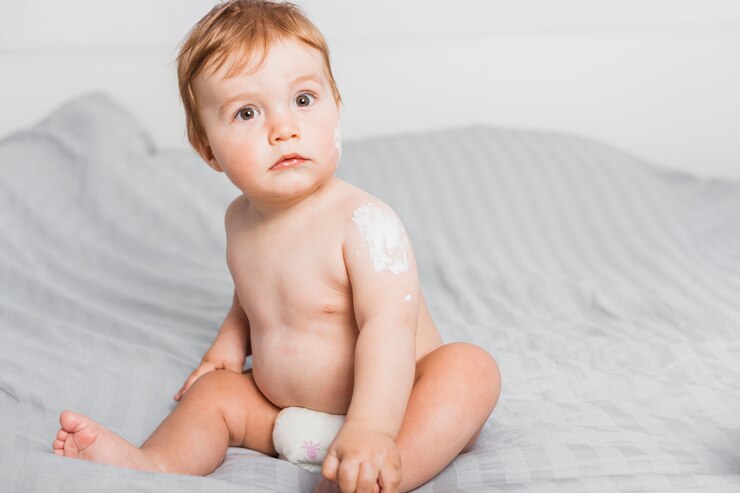 Foto grátis bebê sentado espalhar com loção