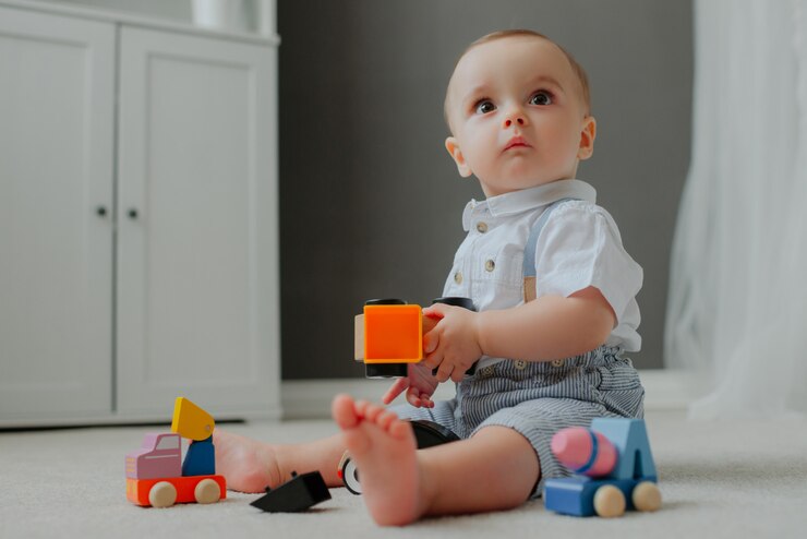 Foto grátis bebê sentado no chão com brinquedos e surpreso.