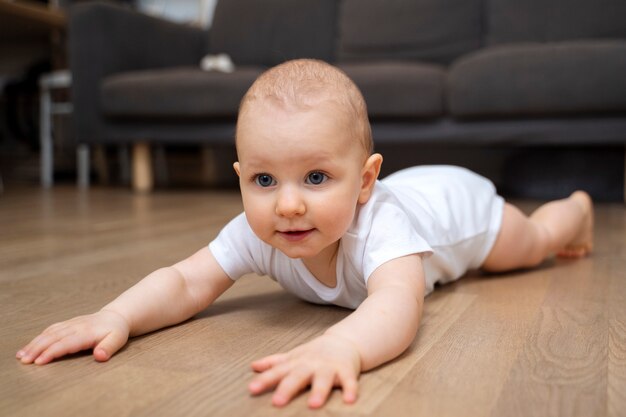 Bebê sorridente de alto ângulo deitado no chão