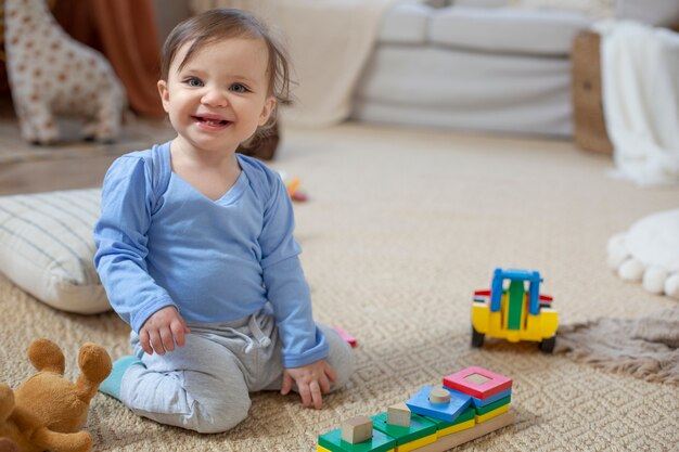 Bebê sorridente de tiro completo no chão