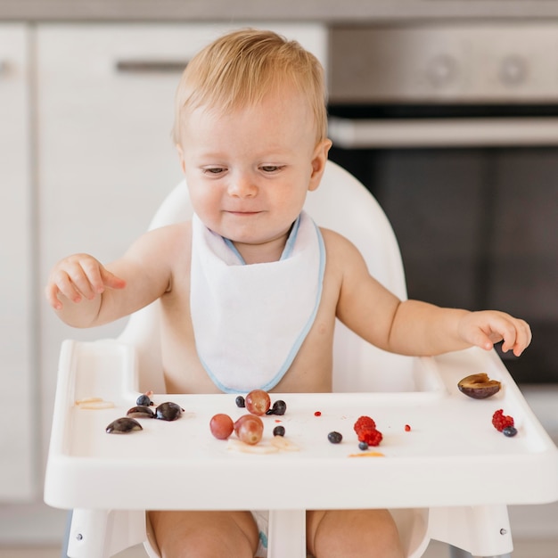 Foto grátis bebê sorridente fofo comendo sozinho