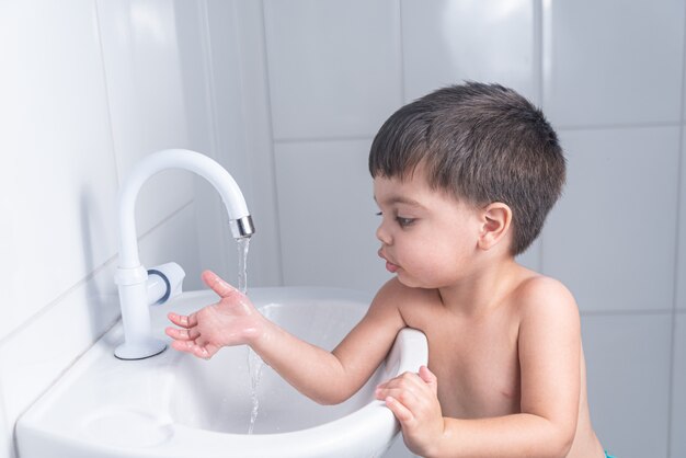 Bebezinho fofo lavando as mãos na pia do banheiro