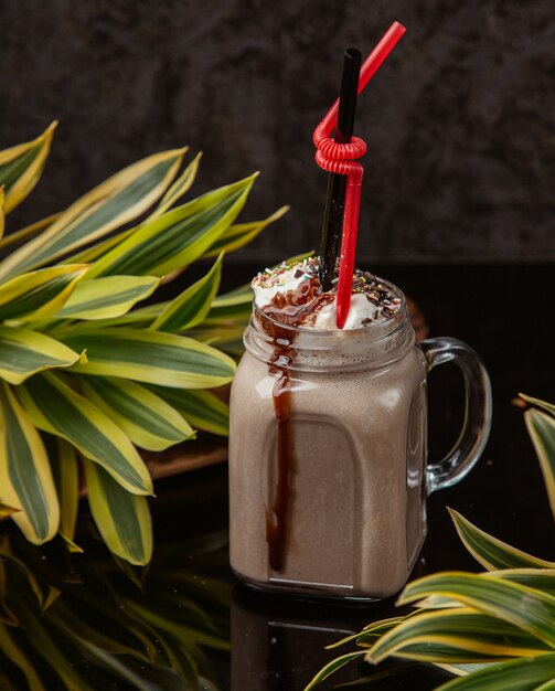 bebida de chocolate em um frasco de vidro com chantilly, granulado e calda de chocolate por cima