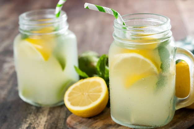 Bebida de limonada em uma jarra de vidro e ingredientes na mesa de madeira xA