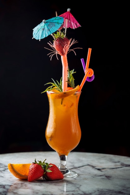 Bebida de verão laranja cocktail com tubos e guarda-chuvas.