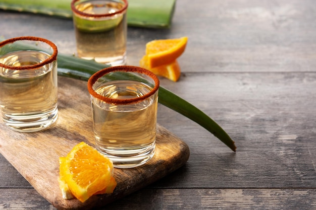 Bebida mexicana de mezcal com fatias de laranja e sal de minhoca na mesa de madeira