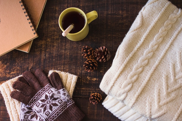 Bebida quente e cones perto de notebook e roupas de malha