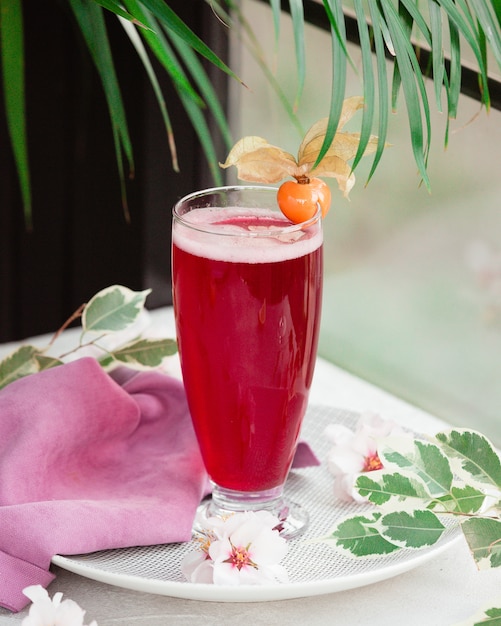 Bebida vermelha com espuma e flor berry.