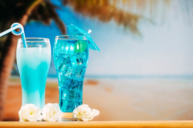 Bebidas azuis com palha no guarda-chuva decorado óculos e flores