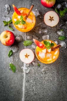 Bebidas tradicionais de outono, coquetéis de mojito de cidra de maçã com menta, canela e gelo. na mesa de pedra preta, copie a vista superior do espaço