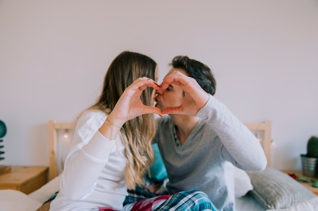 Foto grátis beijando casal fazendo um gesto de coração