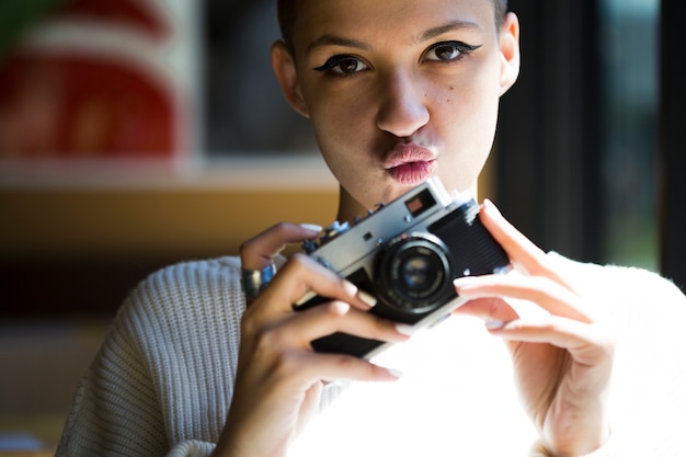 Beijando, mulher, com, câmera vintage, olhando câmera