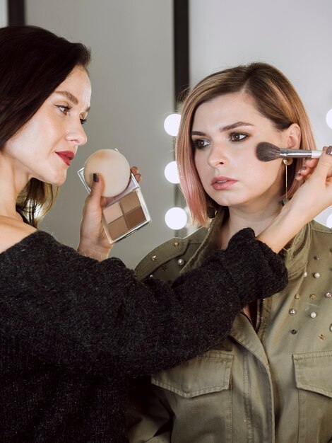 Bela artista aplicando blush no modelo