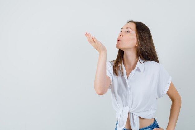 Bela dama de blusa branca mandando beijo no ar e olhando fofa, vista frontal. espaço para texto