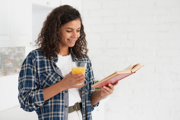 Bela dama lendo um livro e segurando um copo de suco