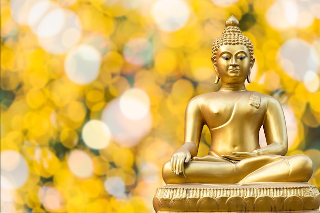 Bela estátua do buda de ouro antigo em fundo de bokeh amarelo dourado claro, conceito de férias na tailândia