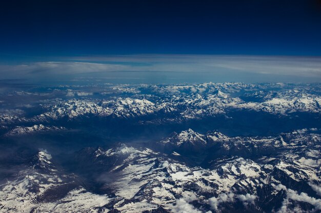 Bela foto aérea de um cenário montanhoso nevado sob o céu azul de tirar o fôlego