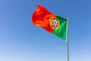 Foto grátis bela foto da bandeira portuguesa balançando no céu calmo e brilhante