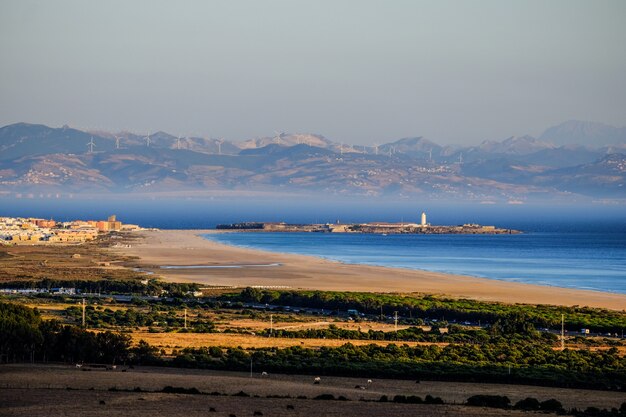 Bela foto da costa perto das árvores e montanha ao longe