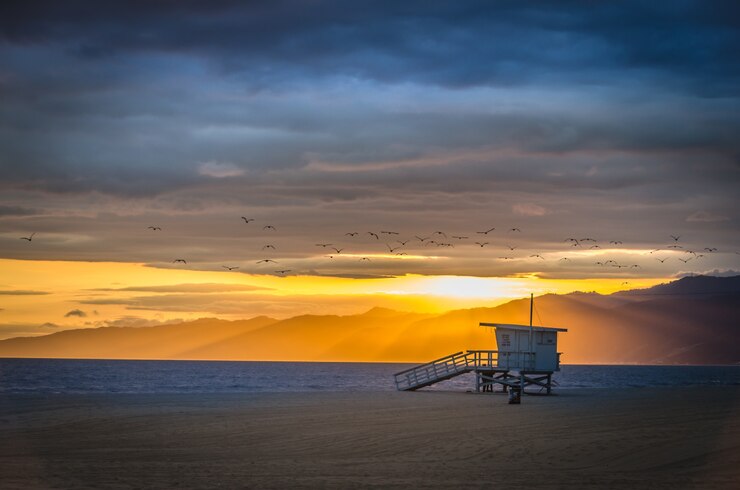 Foto grátis bela foto da praia de venice com montanhas à distância e um céu nublado ao pôr do sol
