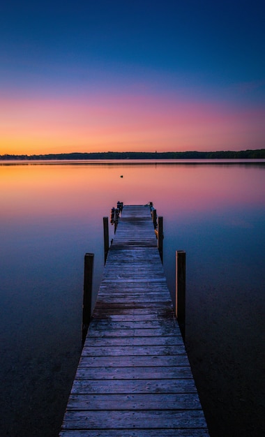 Bela foto das cores do pôr do sol no horizonte de um lago tranquilo com uma doca