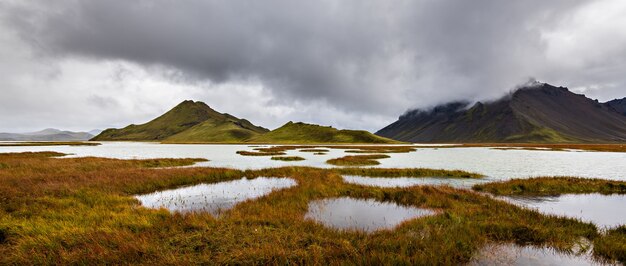 Bela foto das montanhas na região das Terras Altas da Islândia, com um céu nublado e cinza ao fundo