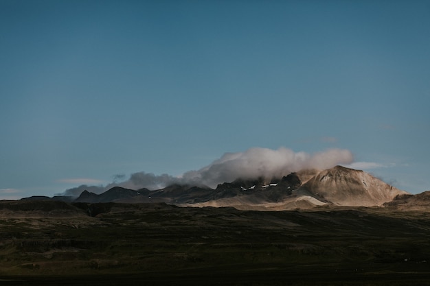 Bela foto de colinas rochosas cobertas por nuvens brancas em um terreno verde