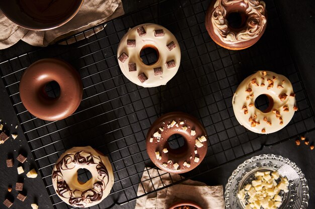 Bela foto de deliciosos donuts cobertos de esmalte e pedaços de chocolate em uma mesa preta