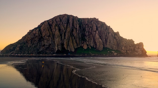 Bela foto de falésias rochosas perto de uma praia com luz solar do lado
