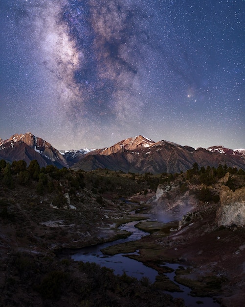 Bela foto de montanhas e colinas cobertas de neve com a Via Láctea em um céu estrelado