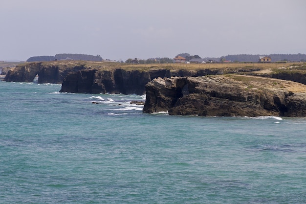 Bela foto de montanhas rochosas banhadas pelas ondas azuis do oceano