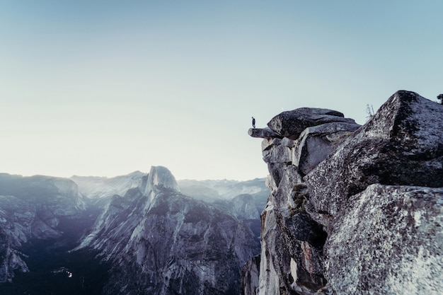 Bela foto de montanhas rochosas com uma pessoa de pé na beira