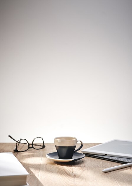 Bela foto de óculos ópticos e uma xícara em uma mesa com um fundo branco e espaço para texto