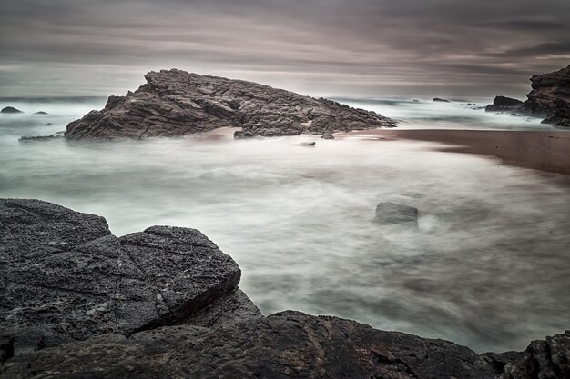 Bela foto de pedras à beira-mar com um céu sombrio no