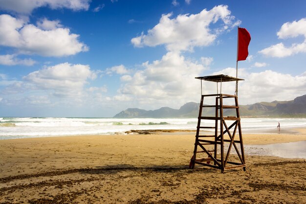 Bela foto de um assento de salva-vidas na praia com uma bandeira vermelha em Maiorca