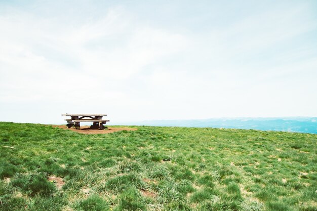 Bela foto de um banco e uma mesa no campo de grama