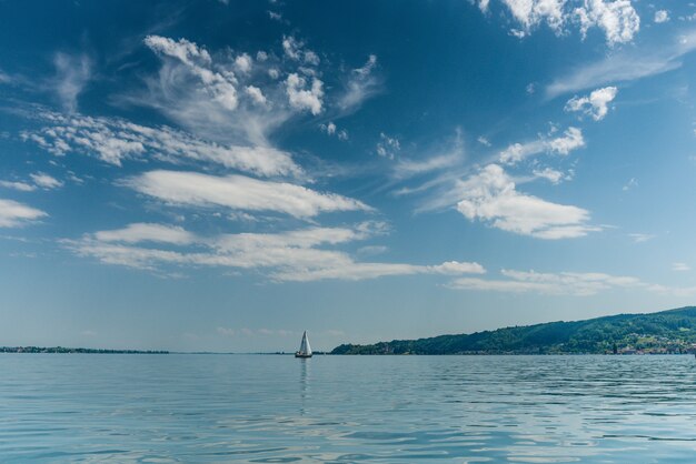 Bela foto de um barco navegando em um mar calmo com colinas no lado direito